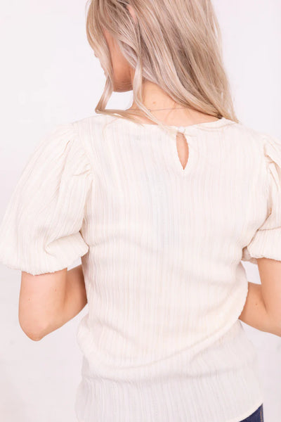 This Puff Sleeve Top in Egret is the perfect piece to add some oomph to your wardrobe. With a textured fabric and elastic puff sleeve, it's sure to be a conversation starter. Plus, a key hole closure in the back? Now that's a playful top with serious style!